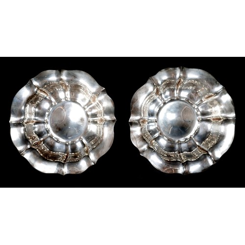 130 - A pair of Victorian silver pedestal bowls, each of lobed oval form raised on a stepped and shaped ci... 