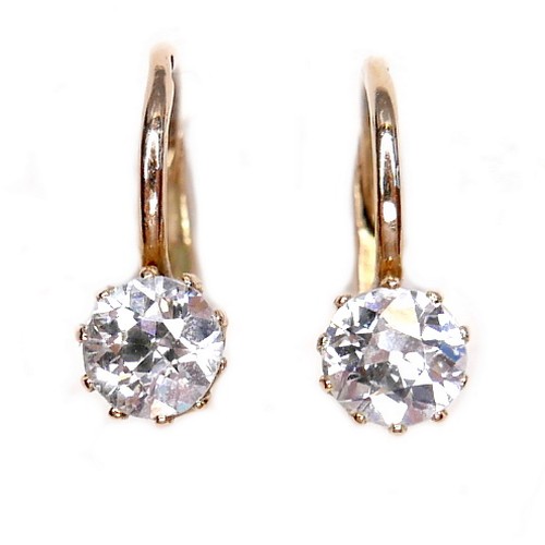 362 - A pair of diamond solitaire earrings, on fixed loop settings with hinged clasp, each brilliant cut s... 