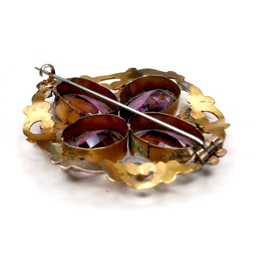 250 - A Victorian gilt brass brooch set with amethysts, the four oval stones each 18 by 12 by 6mm, and of ... 