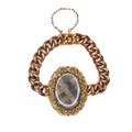 A Victorian gilt brass memento mori pendant with woven lock of hair within, with two attached rose g... 