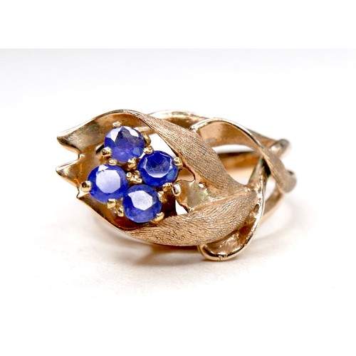 260 - A gold dress ring in the form of a flower, set with four small cornflower blue sapphires, marks rubb... 