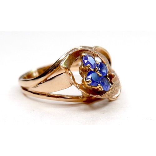 260 - A gold dress ring in the form of a flower, set with four small cornflower blue sapphires, marks rubb... 