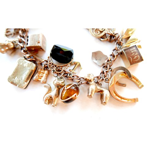 390 - A 9ct rose gold charm bracelet, kerb link with heart padlock clasp, fitted with twenty-one mostly 9c... 