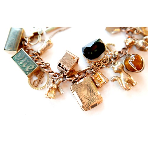 390 - A 9ct rose gold charm bracelet, kerb link with heart padlock clasp, fitted with twenty-one mostly 9c... 