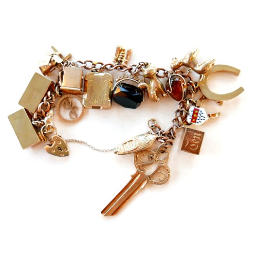 390 - A 9ct rose gold charm bracelet, kerb link with heart padlock clasp, fitted with twenty-one mostly 9c... 