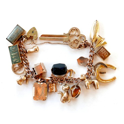 390 - A 9ct rose gold charm bracelet, kerb link with heart padlock clasp, fitted with twenty-one mostly 9c... 