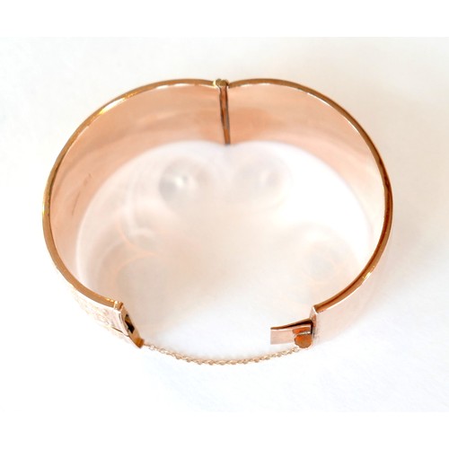 368 - An Edwardian 9ct rose gold hinged cuff bangle, the body half engraved with foliate scrolls, with saf... 