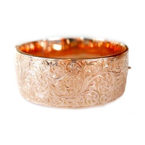 368 - An Edwardian 9ct rose gold hinged cuff bangle, the body half engraved with foliate scrolls, with saf... 