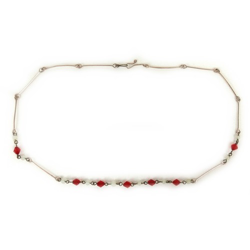 233 - An early 20th century yellow metal necklace with faceted red glass beads and round milk glass beads,... 