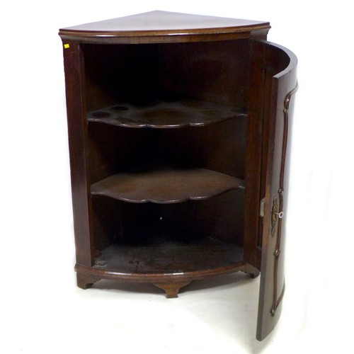 140 - A 19th century mahogany corner cupboard, with single curved panel door enclosing two shaped shelves,... 