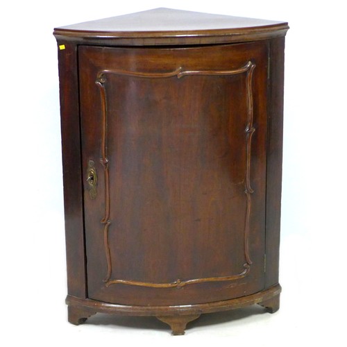 140 - A 19th century mahogany corner cupboard, with single curved panel door enclosing two shaped shelves,... 