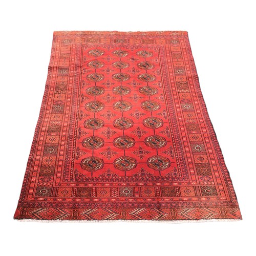 176 - A Turkman rug, red ground with twenty-four medallions to its centre, geometric patterns to its borde... 