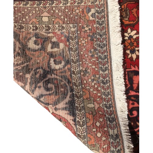 180 - A Bakhtiari rug, with a caucasian central medallion, on red ground with profuse floral decoration, 2... 