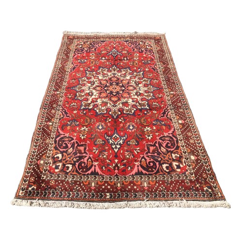 180 - A Bakhtiari rug, with a caucasian central medallion, on red ground with profuse floral decoration, 2... 