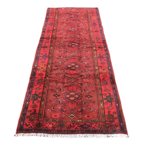 185 - A Karajeh runner, with red ground, foliate and geometric patterns, 304 by 114cm.