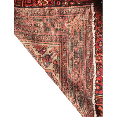 192 - A Hamadan rug, with red ground, caucasian medallion and floral borders, 208 by 150cm.