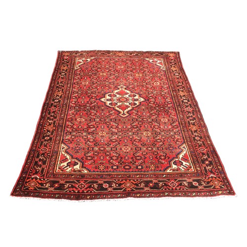 192 - A Hamadan rug, with red ground, caucasian medallion and floral borders, 208 by 150cm.