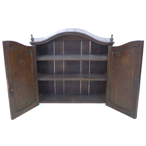 199 - An 18th century oak cupboard, with arched moulded cornice, turned finials, two doors enclosing two s... 