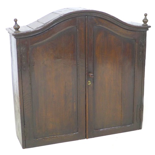 199 - An 18th century oak cupboard, with arched moulded cornice, turned finials, two doors enclosing two s... 