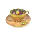 A Royal Worcester tea cup and saucer, painted with fruit to a mossy ground, the cup painted on the i... 