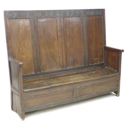 200 - A 17th century oak box settle, with four panel back decoratively carved foliate and lunette frieze, ... 