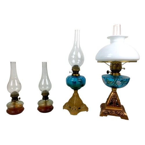 35 - A group of four early 20th century oil lamps, the largest with hand painted font, milk glass shade, ... 