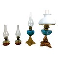 A group of four early 20th century oil lamps, the largest with hand painted font, milk glass shade, ... 