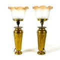 A pair of Art Nouveau brass table lamp bases, with embossed floral decoration, frosted glass shades ... 