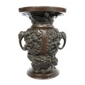A Japanese bronze twin handled vase, Meiji period, decorated in high relief with panels of birds on ... 