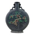 A Chinese moon flask, early 20th century, black pottery with twin dragon handles, decorated in relie... 