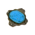 An Egyptian turquoise scarab beetle, mounted upon a white metal mount inlaid with four marcasite sto... 