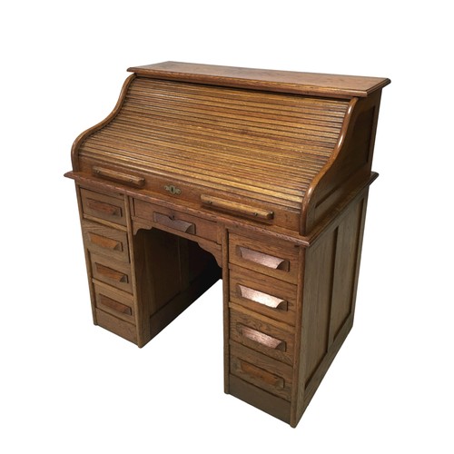 183 - An Edwardian oak roll top desk, fitted with an arrangement of small drawers and pigeon holes behind ... 