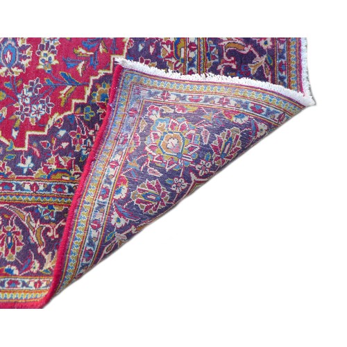 184 - A Kashan rug, on red ground, with blue central lozenge, densely decorated ground with floral and fol... 