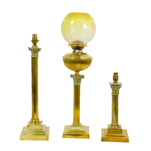 93 - Three brass lamps with Corinthian column style bases, comprising an Edwardian oil lamp with yellow g... 