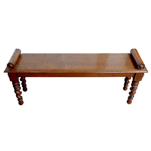 176 - An early 20th century oak window seat, with carved  decoration to its cylindrical arms, raised upon ... 