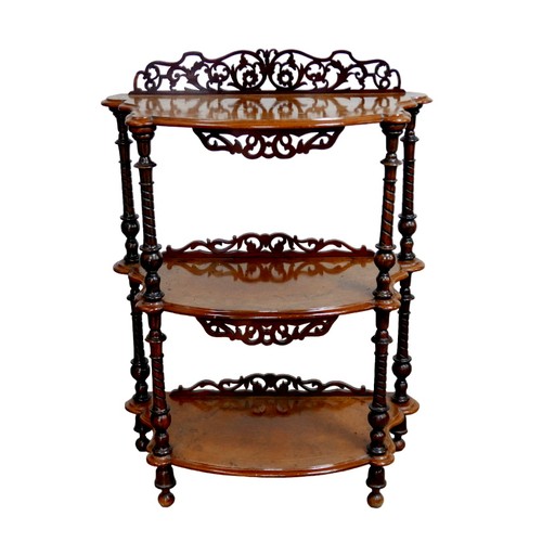 150 - An early 20th century three tiered walnut whatnot, with pierced foliate decoration, turned supports ... 