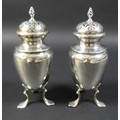 Two Edwardian condiments, both with flame finials, raised upon tripod bases with pad feet, with rubb... 