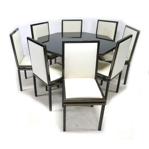 A vintage Pierre Vandel hexagonal dining table and eight matching chairs, with black and silvered finish over a square section tubular construction, the table with glass surface, 131 by 78cm high, the chairs with white padded seats and backs, 45 by 47 by 98cm high. (9)