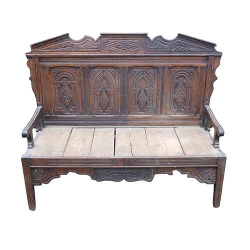 272 - An 18th century oak settle, carved four panel back and removable pediment, open arms, solid plank se... 