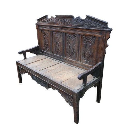 272 - An 18th century oak settle, carved four panel back and removable pediment, open arms, solid plank se... 