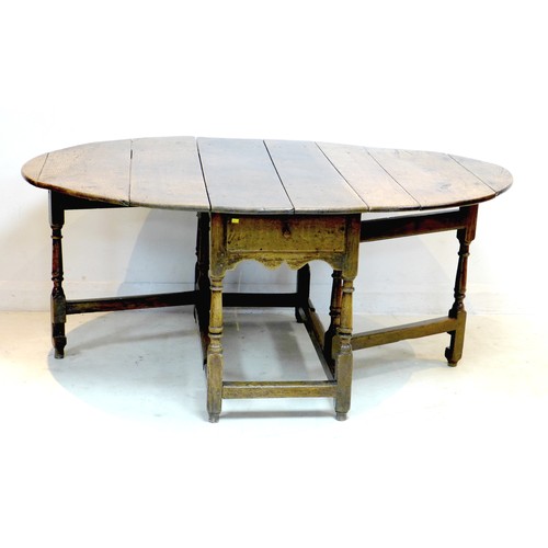 266 - A 17th or 18th century oak drop leaf dining table, with oval surface, twin gate leg action, raised o... 