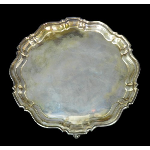 104 - A George V silver tray, of circular form with Chippendale pie crust edge, raised on three scroll fee... 