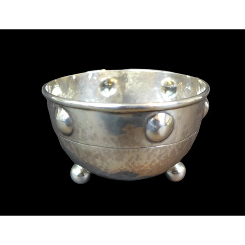 9 - A George V Arts & Crafts silver sugar bowl, of circular form with planished main body raised upon th... 