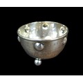 A George V Arts & Crafts silver sugar bowl, of circular form with planished main body raised upon th... 