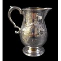A George V silver milk jug, of baluster form, with double C scroll handle, repousse foliate decorati... 