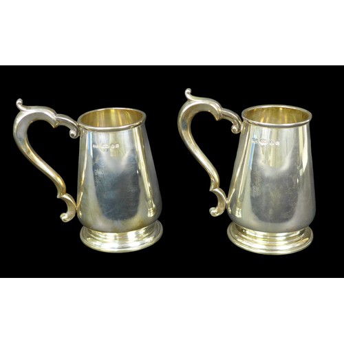 93 - A pair of Elizabeth II silver tankards, each of tapering bellied form with scroll handle, import mar... 