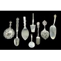 Eight pieces of British and international silver and white metal, comprising two tea straining spoon... 