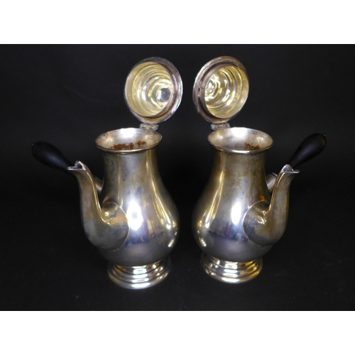 62 - A pair of George V silver chocolate pots, of bellied form with side spouts, turned ebonised handles ... 