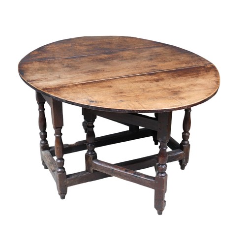 246 - A late 18th century oak drop leaf table, with oval top, two gate legs with turned supports, fully ex... 