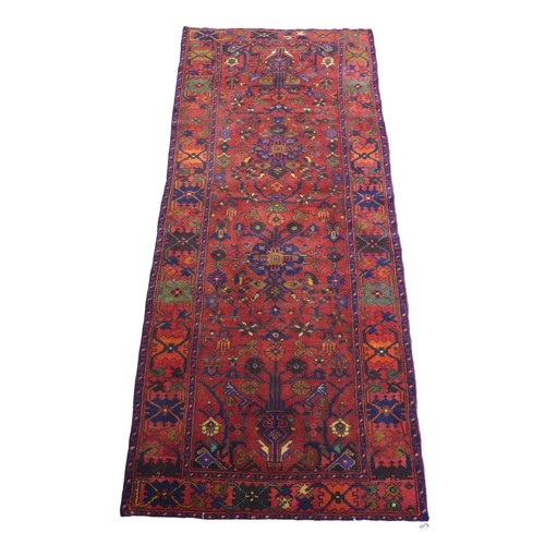 266 - A Karajeh runner, on red ground, with foliate and geometric patterns, 290 by 125cm.